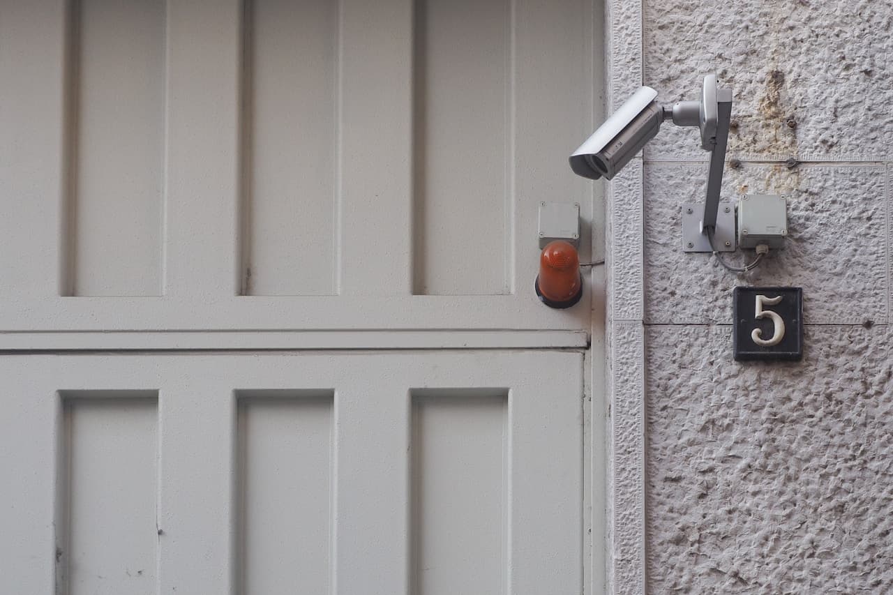 Wall-mounted security camera by a residential entrance.