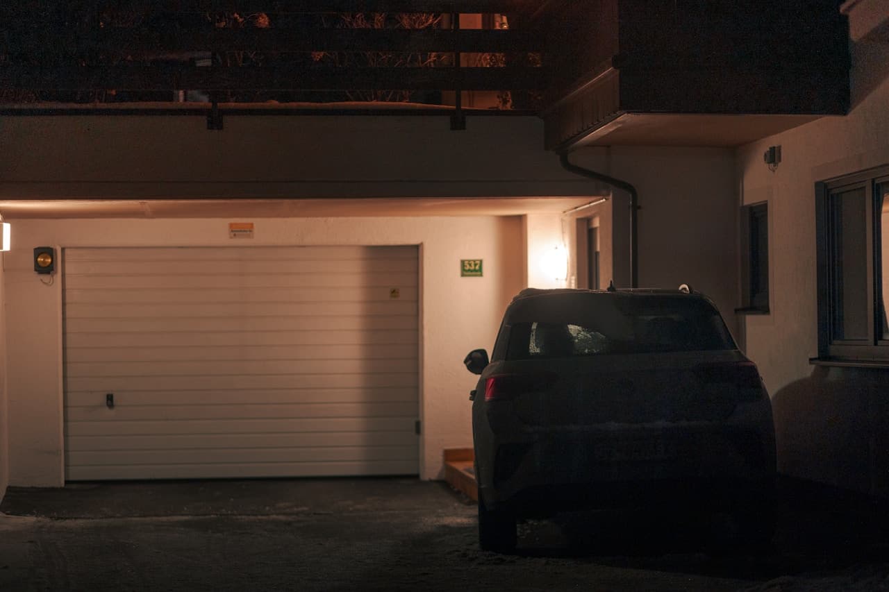 Night view of a secured driveway and parked car.